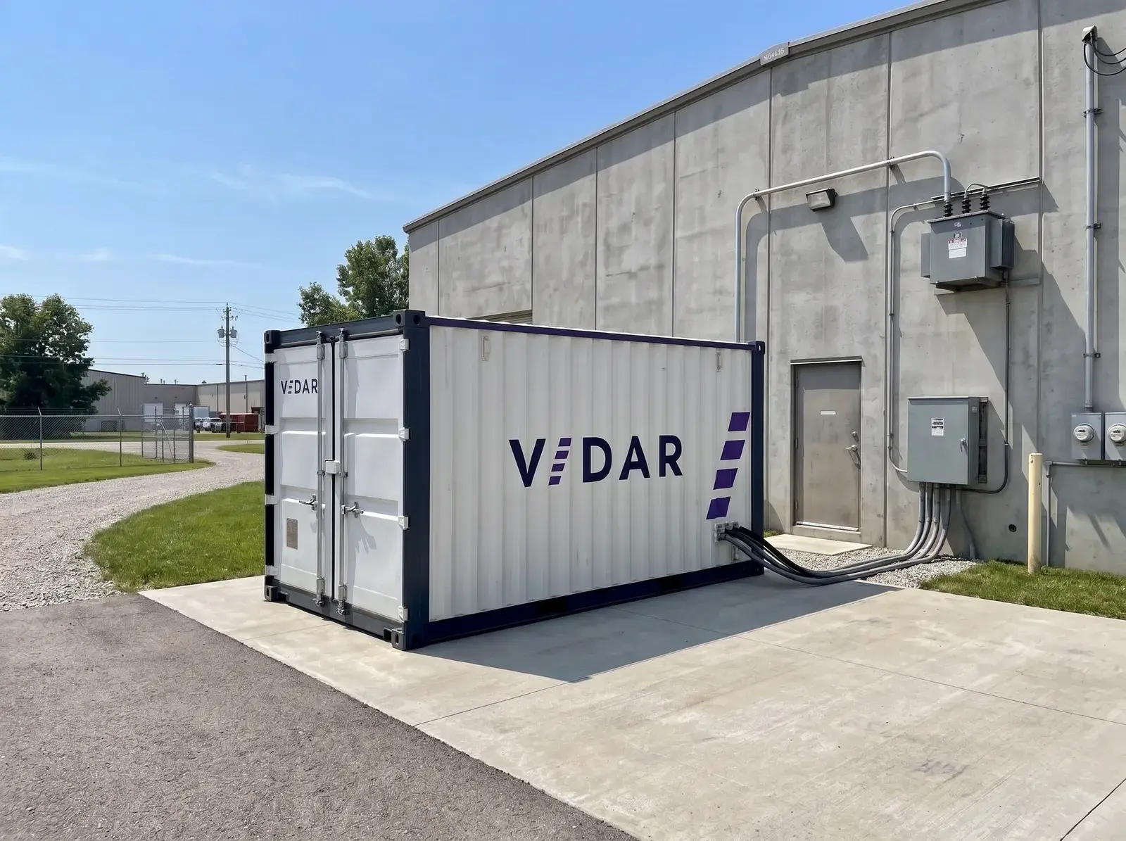 Vidar-batterijcontainer op een betonplaat naast een bedrijfshal